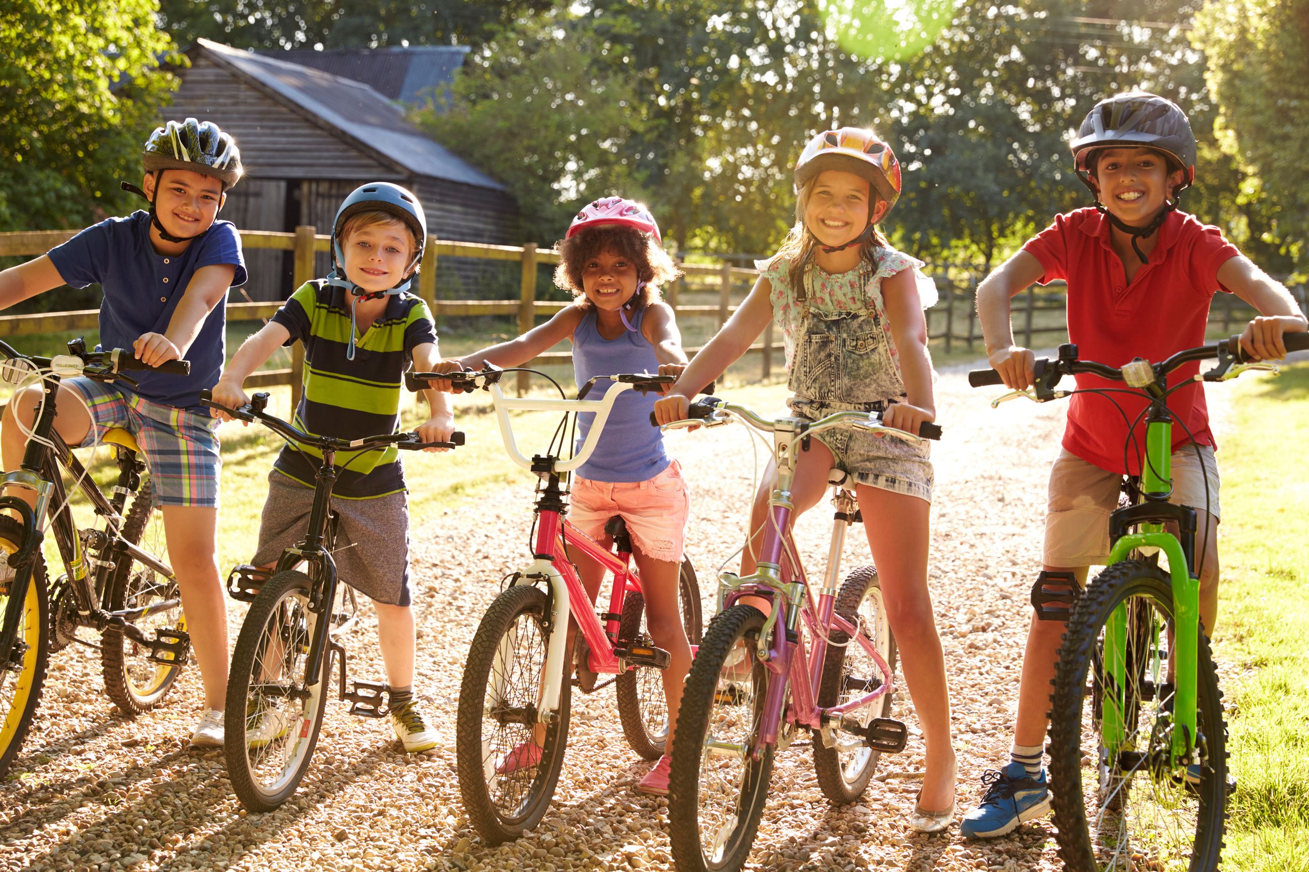 Group of children riding bikes and wearing protective gear.
