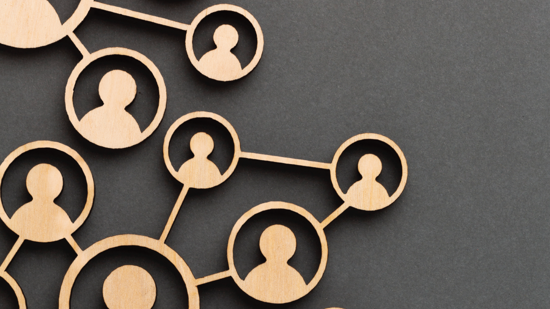Picture of wood cutouts of people in an org chart configuration on a grey background