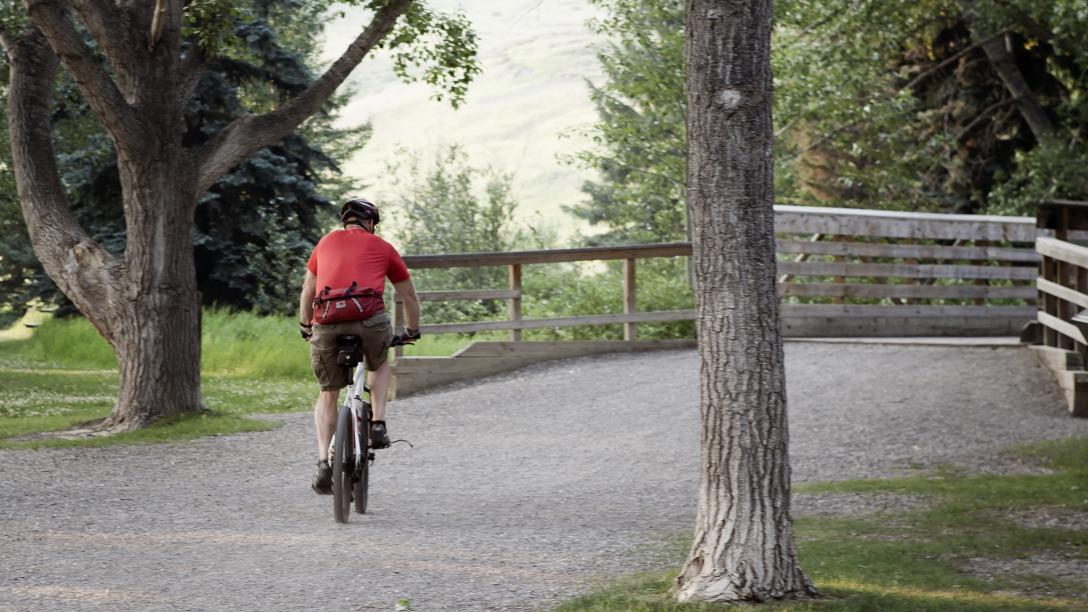 man in red shirt biking down a pathway 