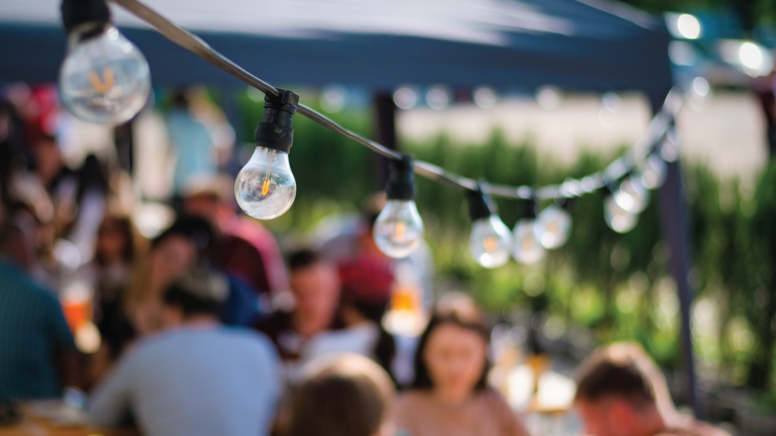 people outside gathering with string lights in the foreground