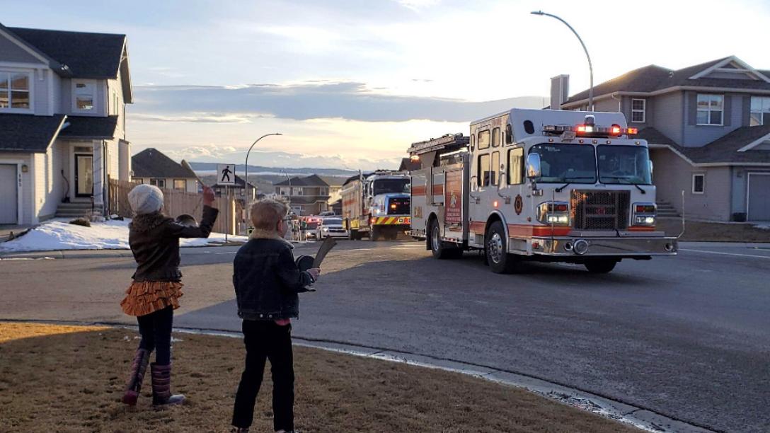 two kids waving to fire truck