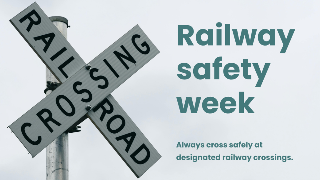 Railway crossing sign beside text reading “Railway Safety Week. Always cross safely at designated railway crossings.”