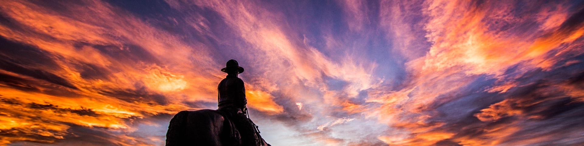 sunset with a statue of a man on a horse