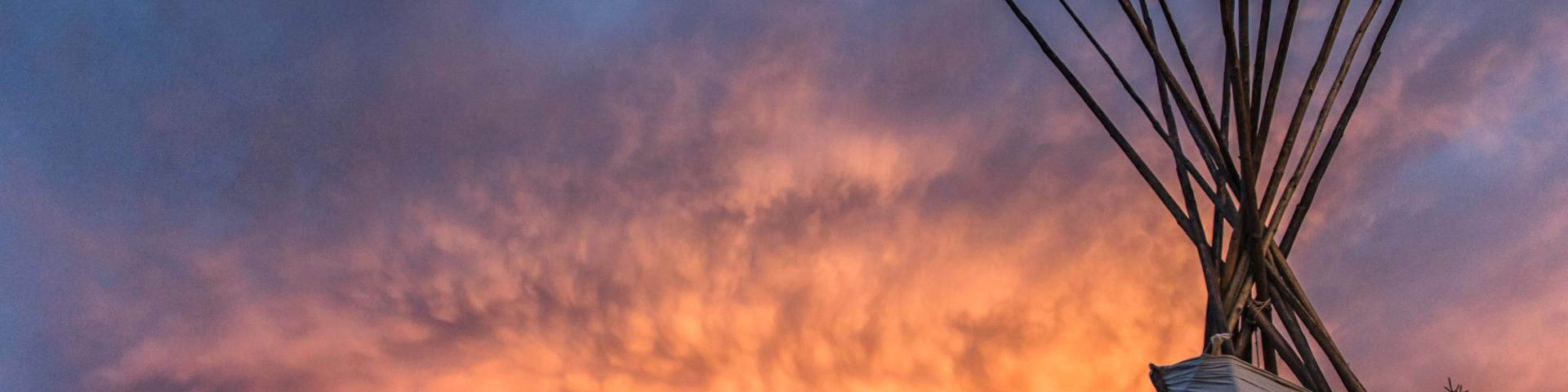 image of tipi with sunset behind it 