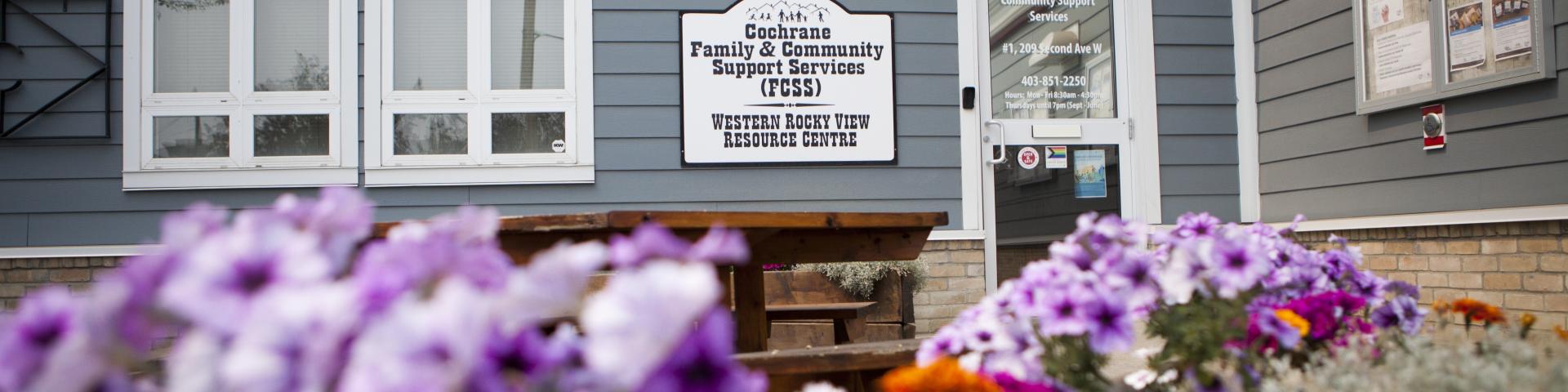 A bunch of flowers surrounding the front of the blue FCSS building