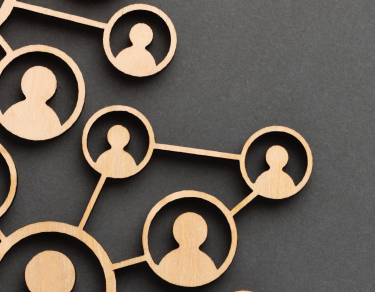 Picture of wood cutouts of people in an org chart configuration on a grey background
