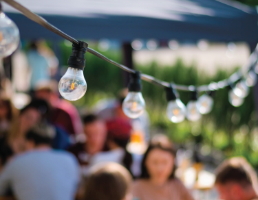 people outside gathering with string lights in the foreground