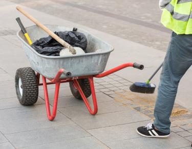 road cleaning person sweeping sidewalk