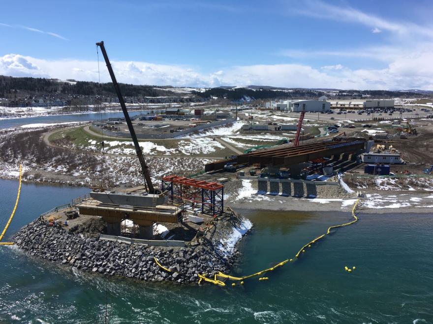 Construction crane unloading materials near the water by the bridge site.