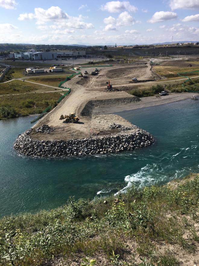 Heavy construction machinery land-filling with rocks and gravel for bridge construction.