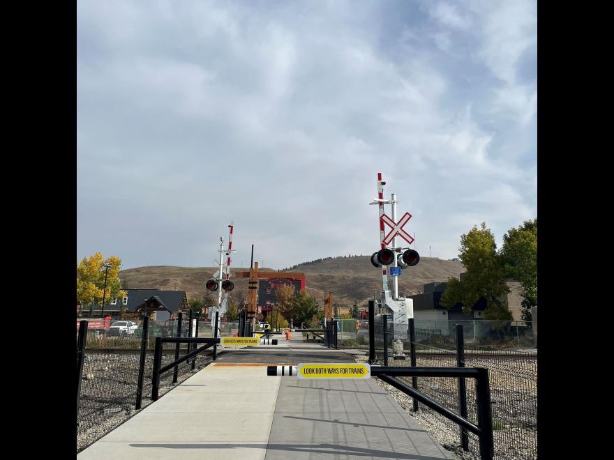 Railroad crossing with signage. The sky is blue and cloudy.