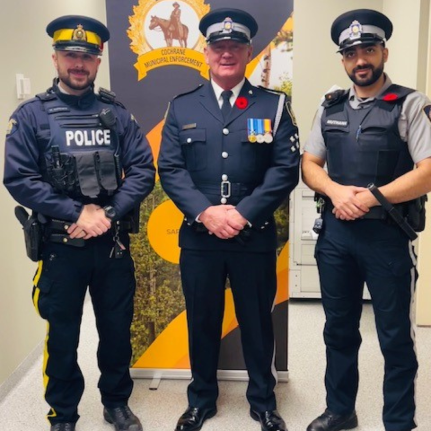 three officers posing in front of banner 