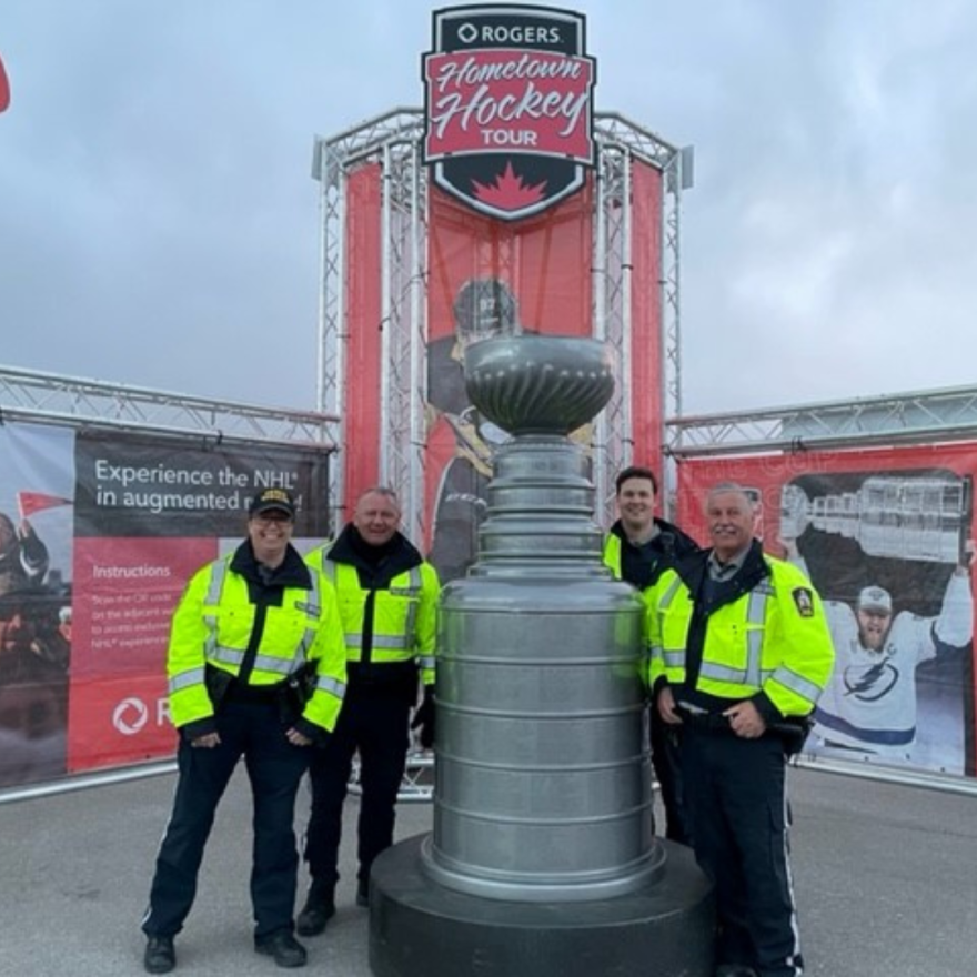 officers posing beside stanley cup