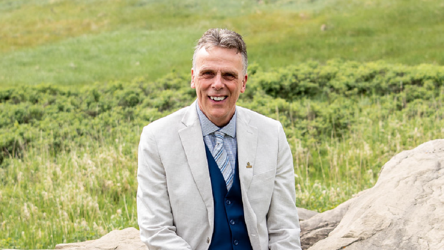 Councillor Reed smiling to camera with green background