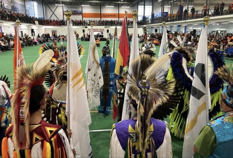 image of individuals lined up at the start of the powwow opening ceremony. 