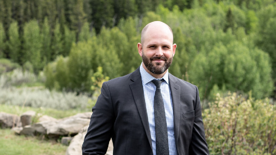 Councillor Wilson smiling to camera with green background