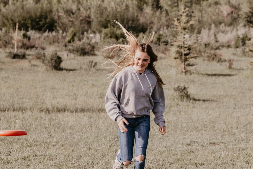 girl running to catch a frisbee