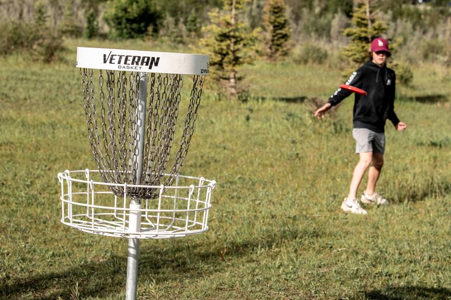 kid throwing frisbee into disc gold net 