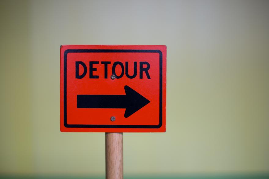 closeup-shot-of-a-red-detour-sign-with-a-black-arrow