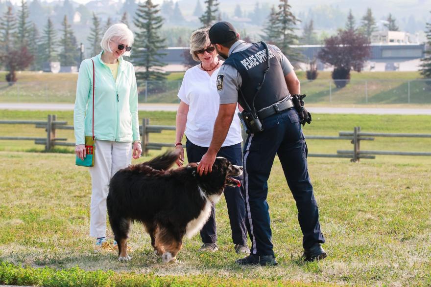 image of peace office petting dog and greeting two ladies 