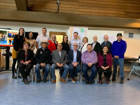 Group photo of representatives from the Bearspaw First Nation, Chiniki First Nation, Goodstoney First Nation, Stoney Tribal Administration and Town Of Cochrane. The front row of people are all sitting on chairs while the people at the back are standing behind them.