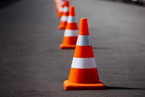 Row of high-vis orange traffic cones. The traffic cones are placed on a road.