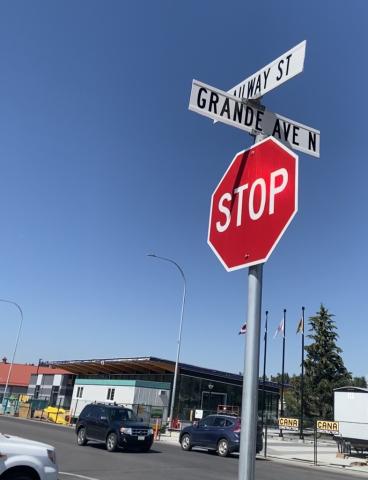 Stop sign at intersection. In the background there is a road with traffic. The sky is blue.
