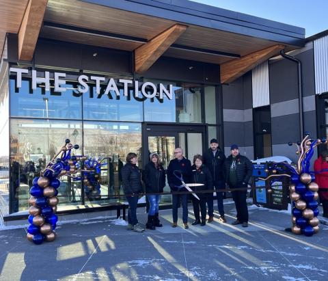 Councillors at opening ceremony for The Station. There is a group of people standing outside of the building surrounded by balloons.