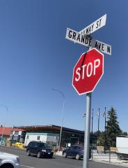 Stop sign at intersection. In the background there is a road with traffic. The sky is blue.