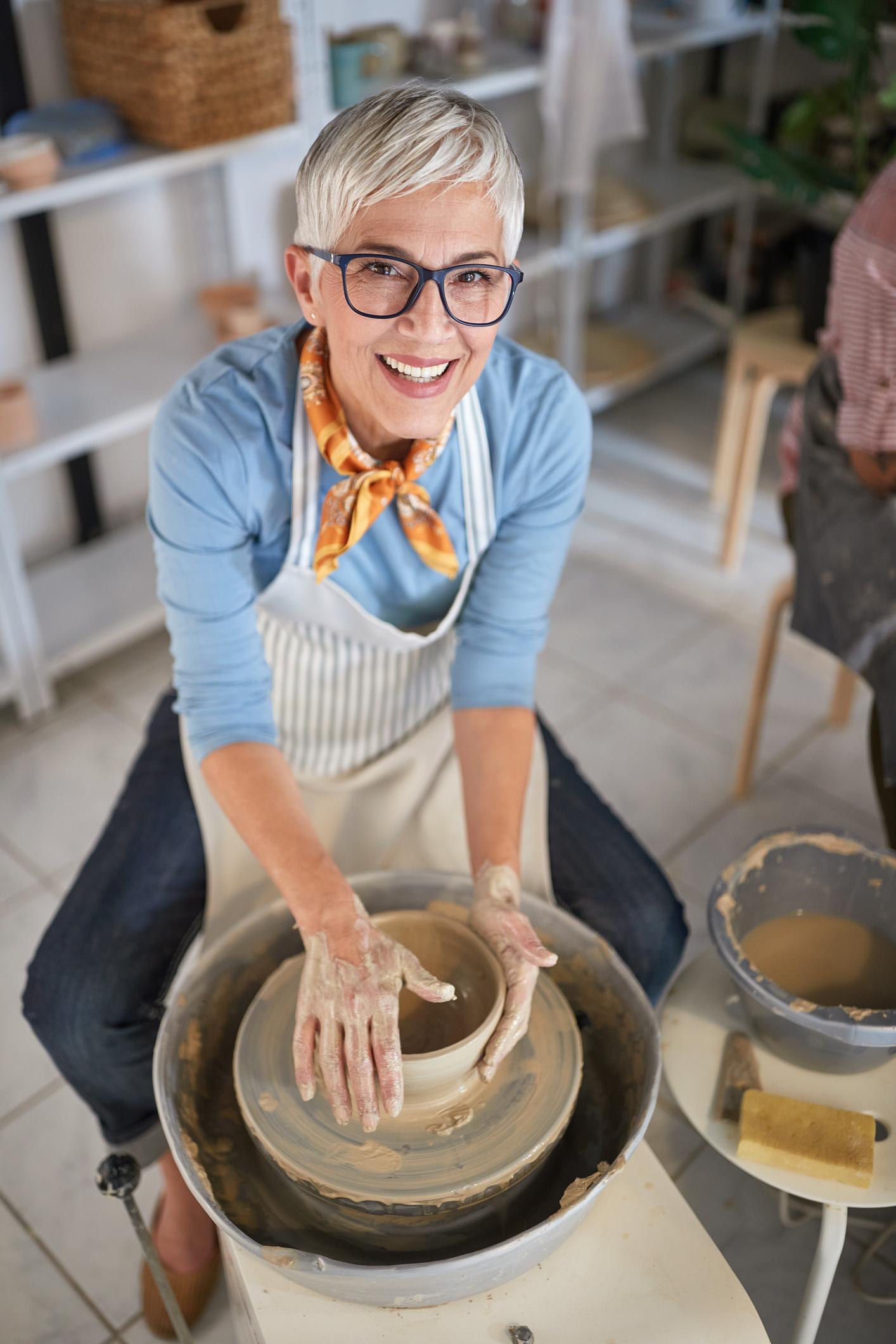 A woman sits at a pottery wheel